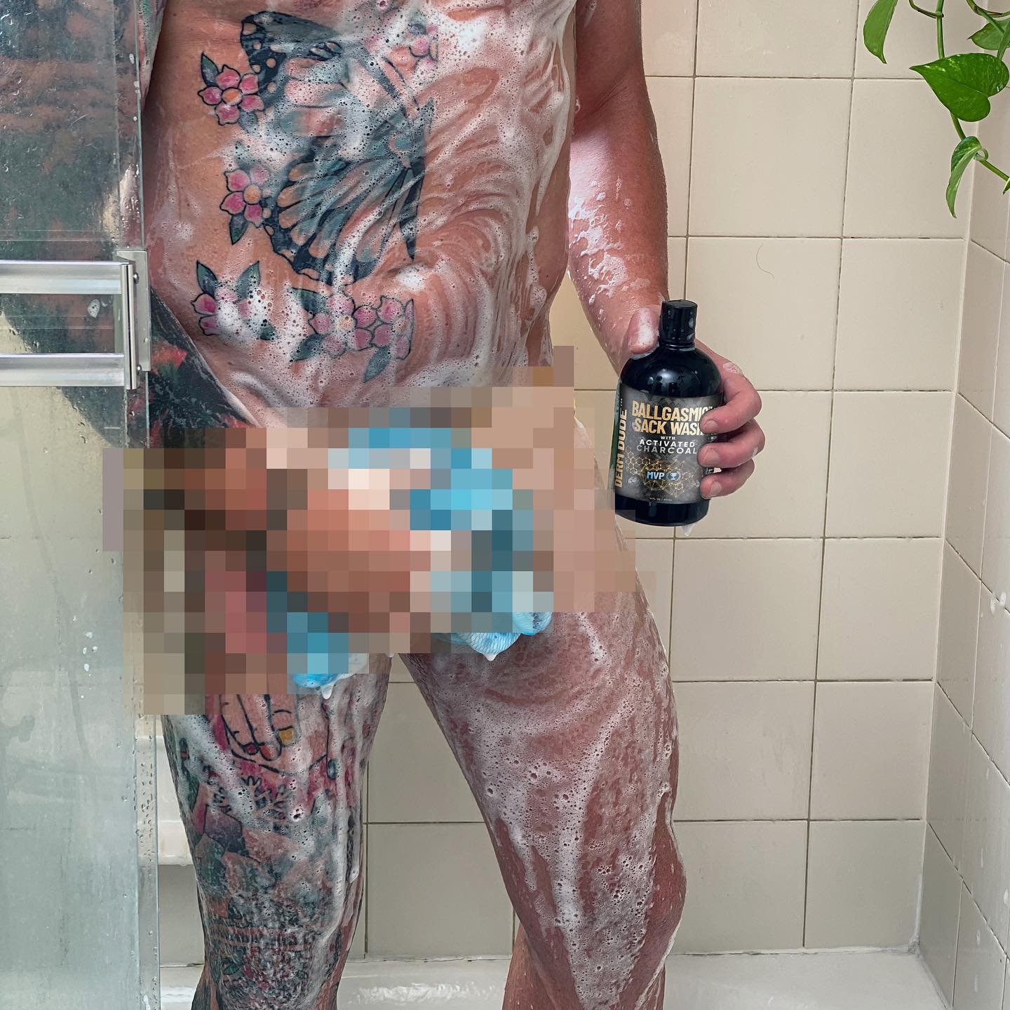 tattooed man taking a shower with visible soap lather 