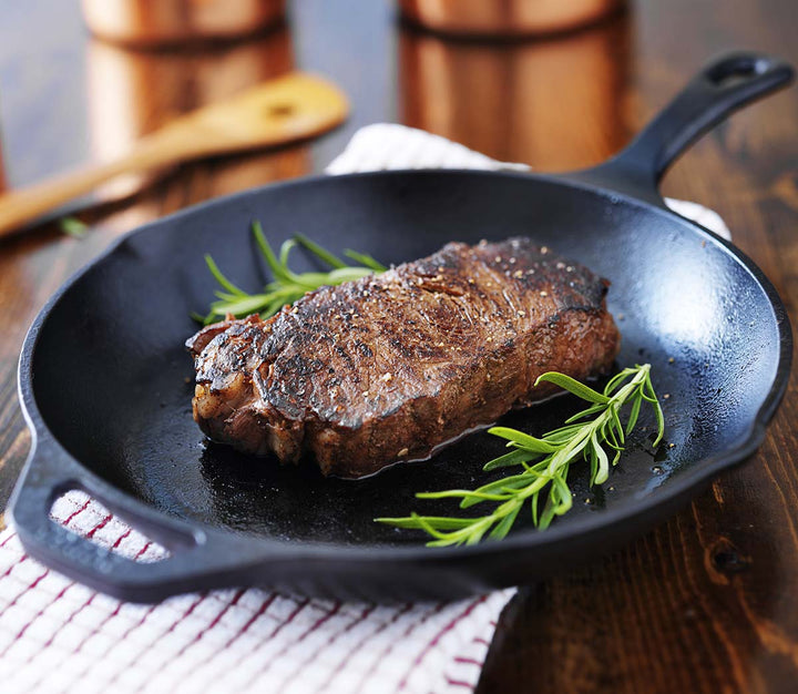 a perfectly cooked and seasoned 12 oz sirloin steak presented in a clean cast iron pan with garnish